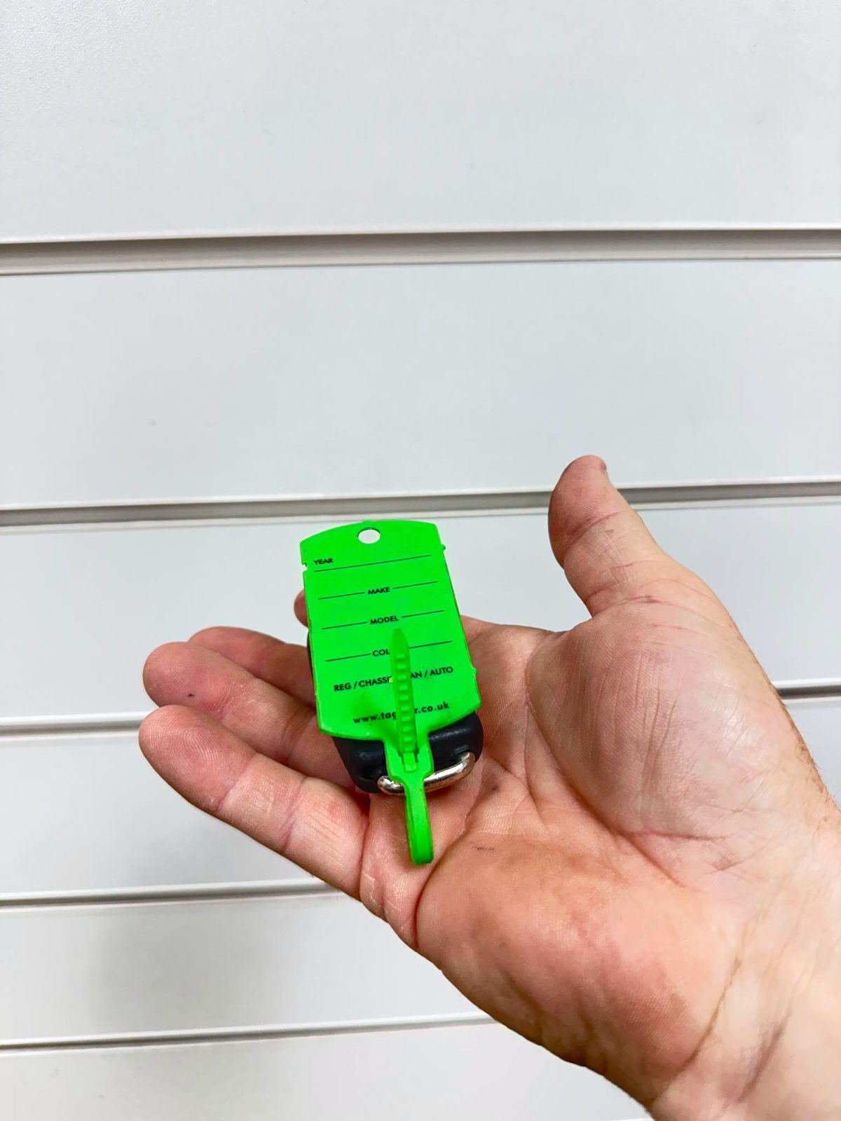 Car keys on a green key tag being handed back to a customer