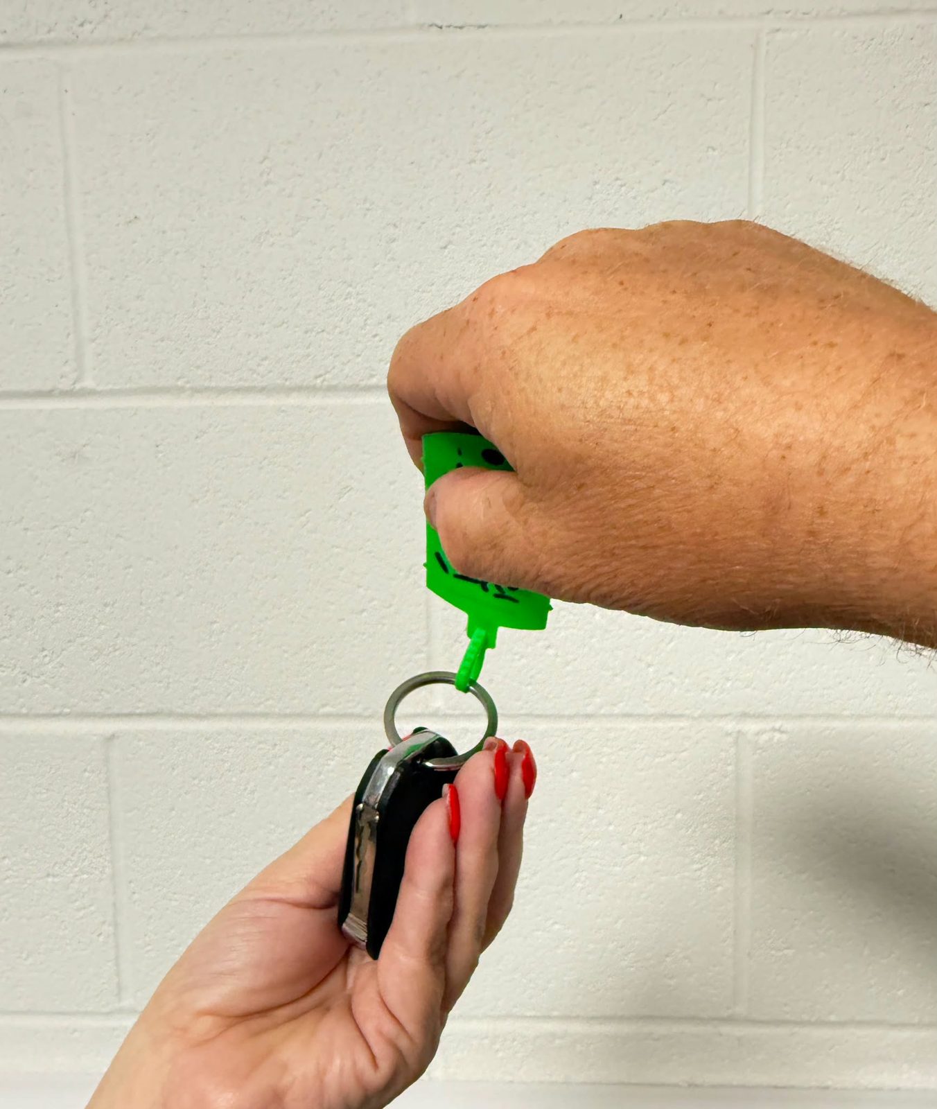 Car keys on a green key tag being handed back to a customer