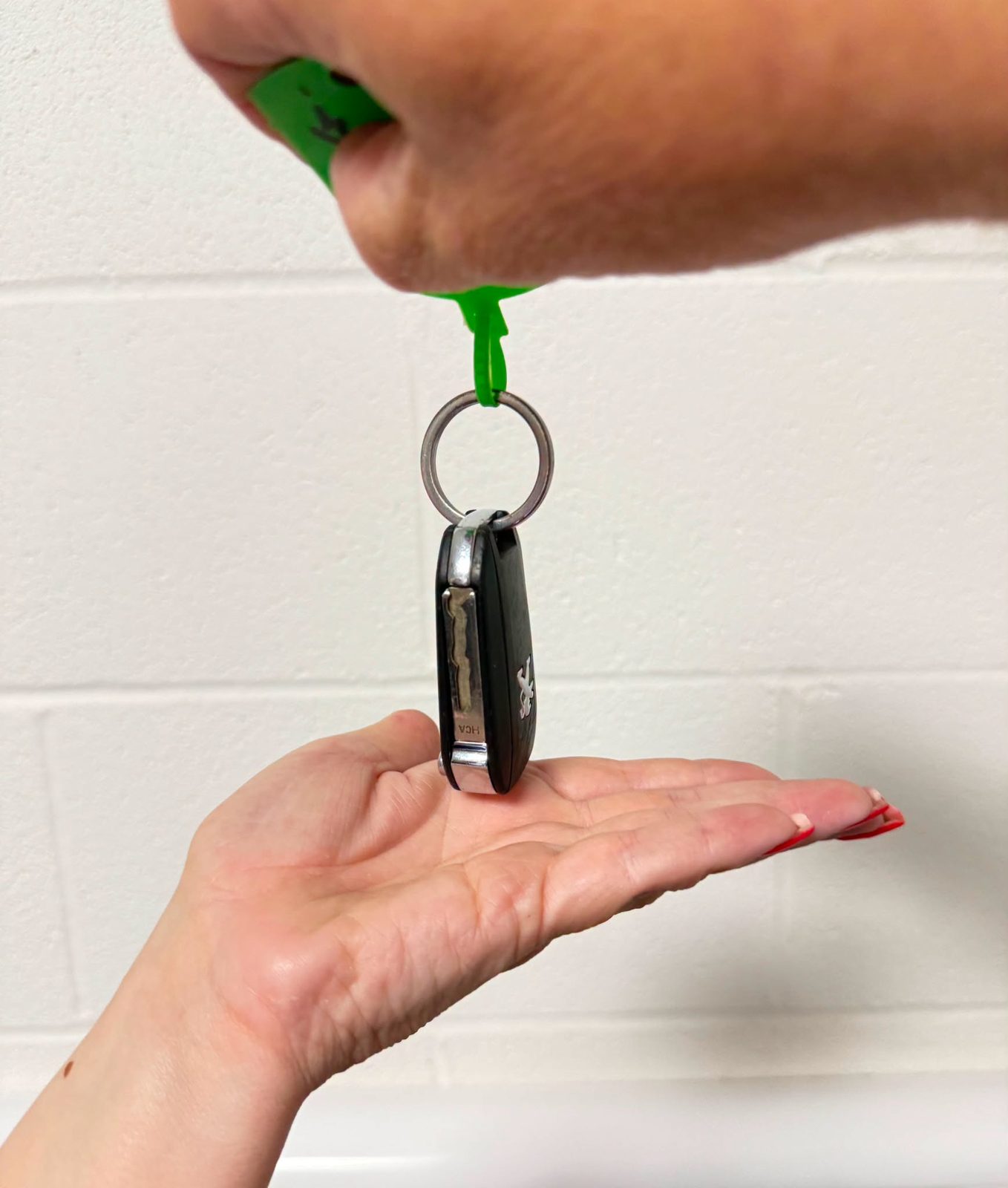 Car keys on a green key tag being handed back to a customer
