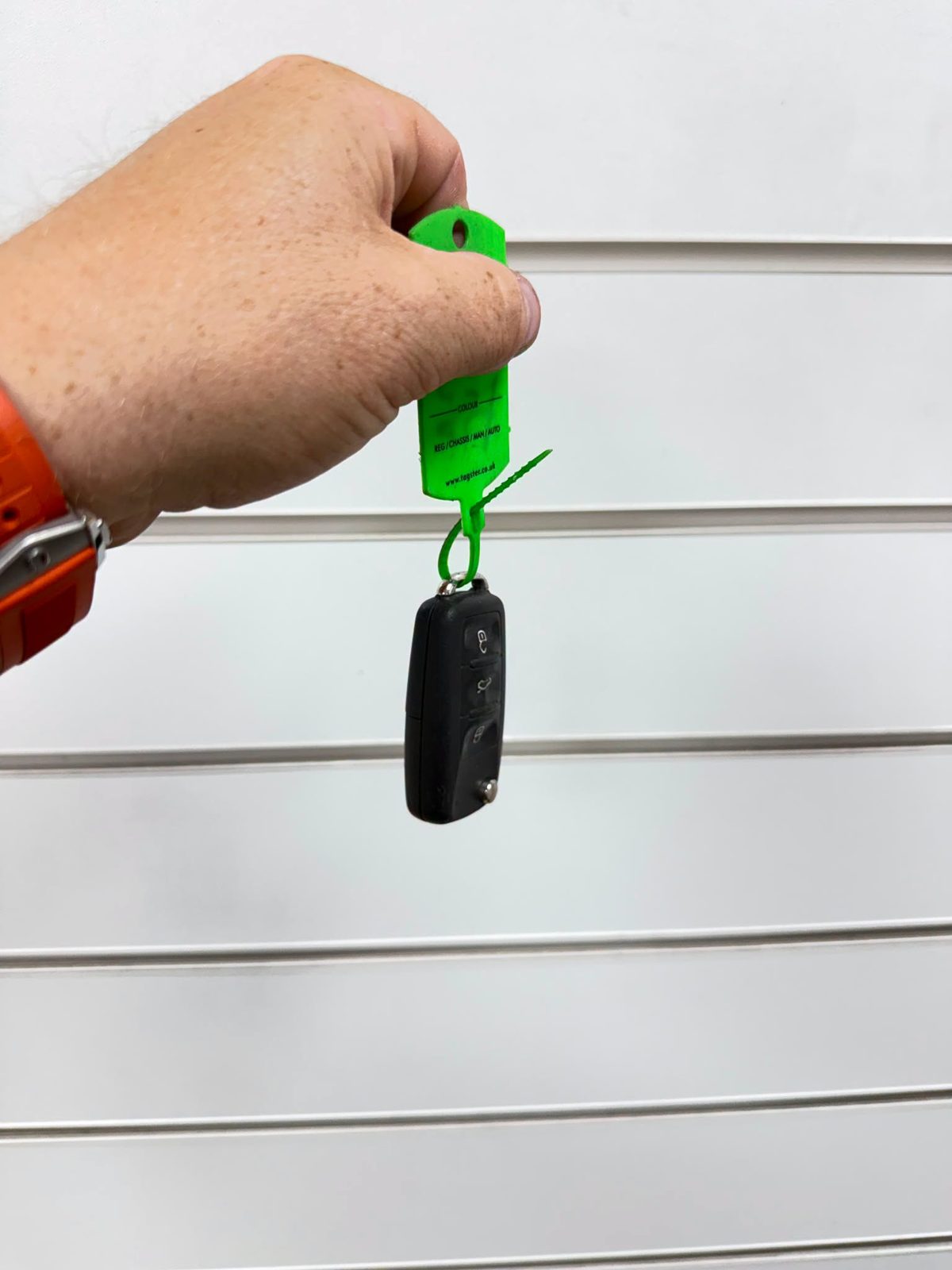 Car keys on a green key tag being handed back to a customer