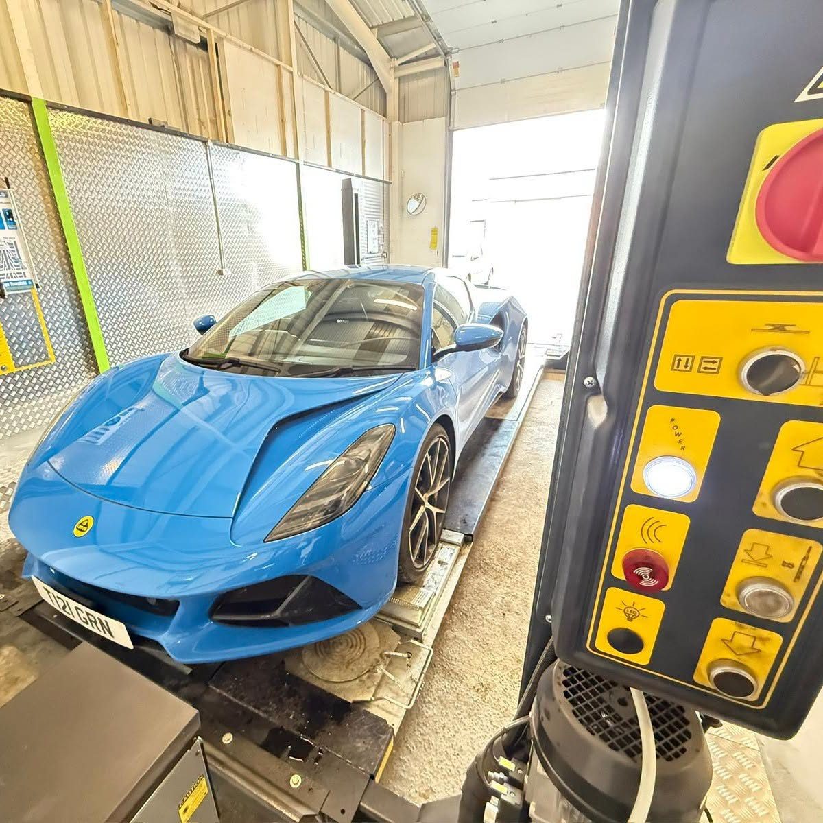 A blue sports car on the MOT lane beside the test controls
