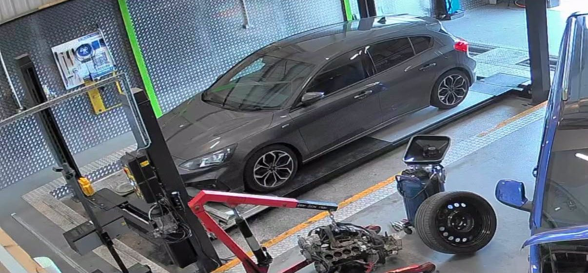 A grey hatchback on the MOT test bay