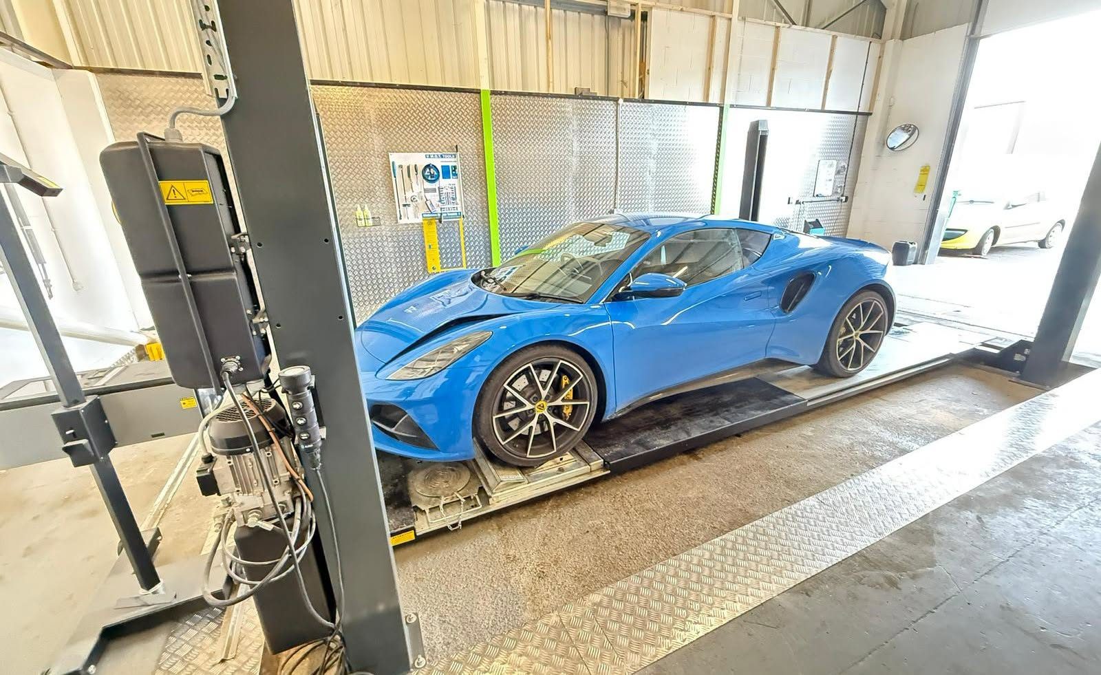 A blue sports car up on a ramp in the workshop